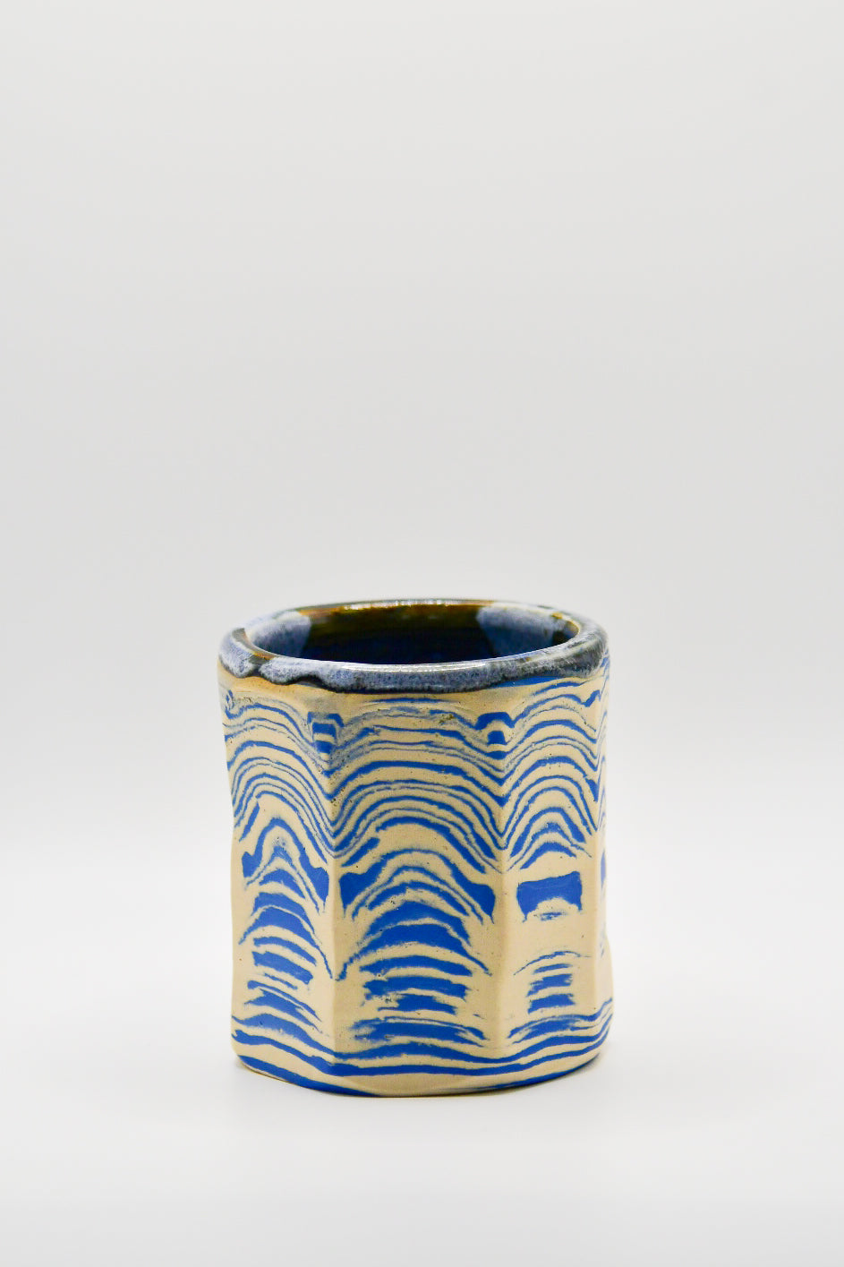 Ceramic cup with blue and beige pattern on a white background