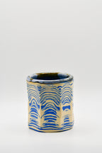 Ceramic cup with blue and beige pattern on a white background