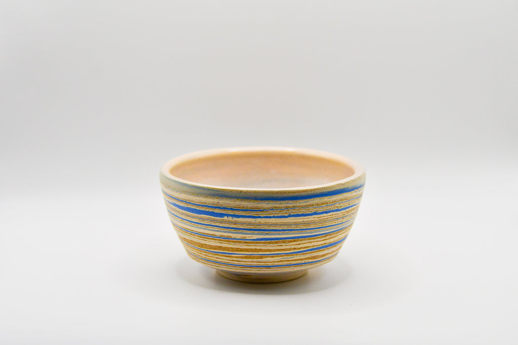 Ceramic bowl with blue and beige stripes on a white background