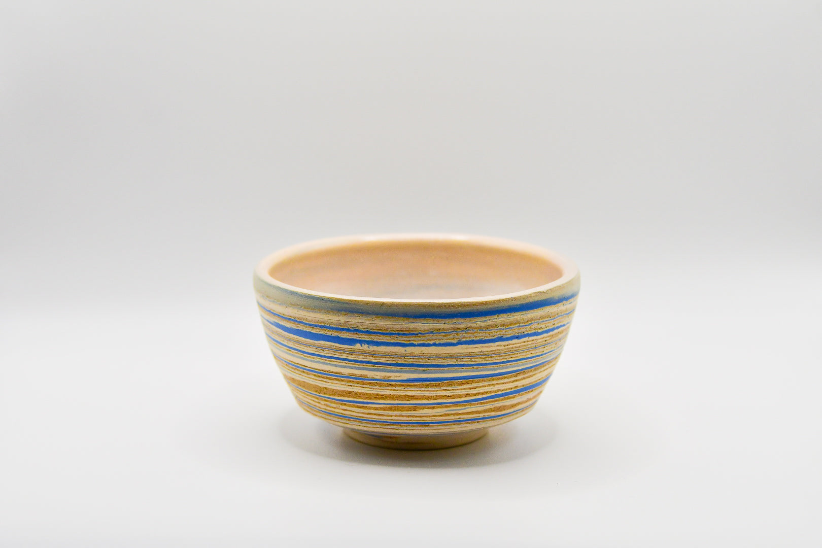 Ceramic bowl with blue and beige stripes on a white background
